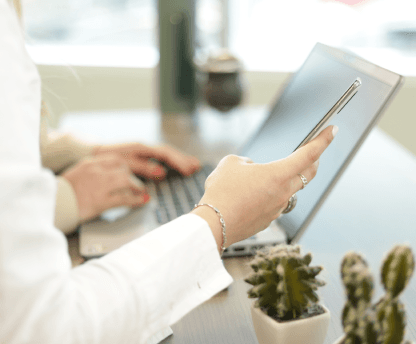 Persona en la computadora sosteniendo su celular.
